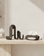 AMINI STRIA Entry Set in Charcoal — book holder and tissue holder on a travertine shelf against a plaster wall