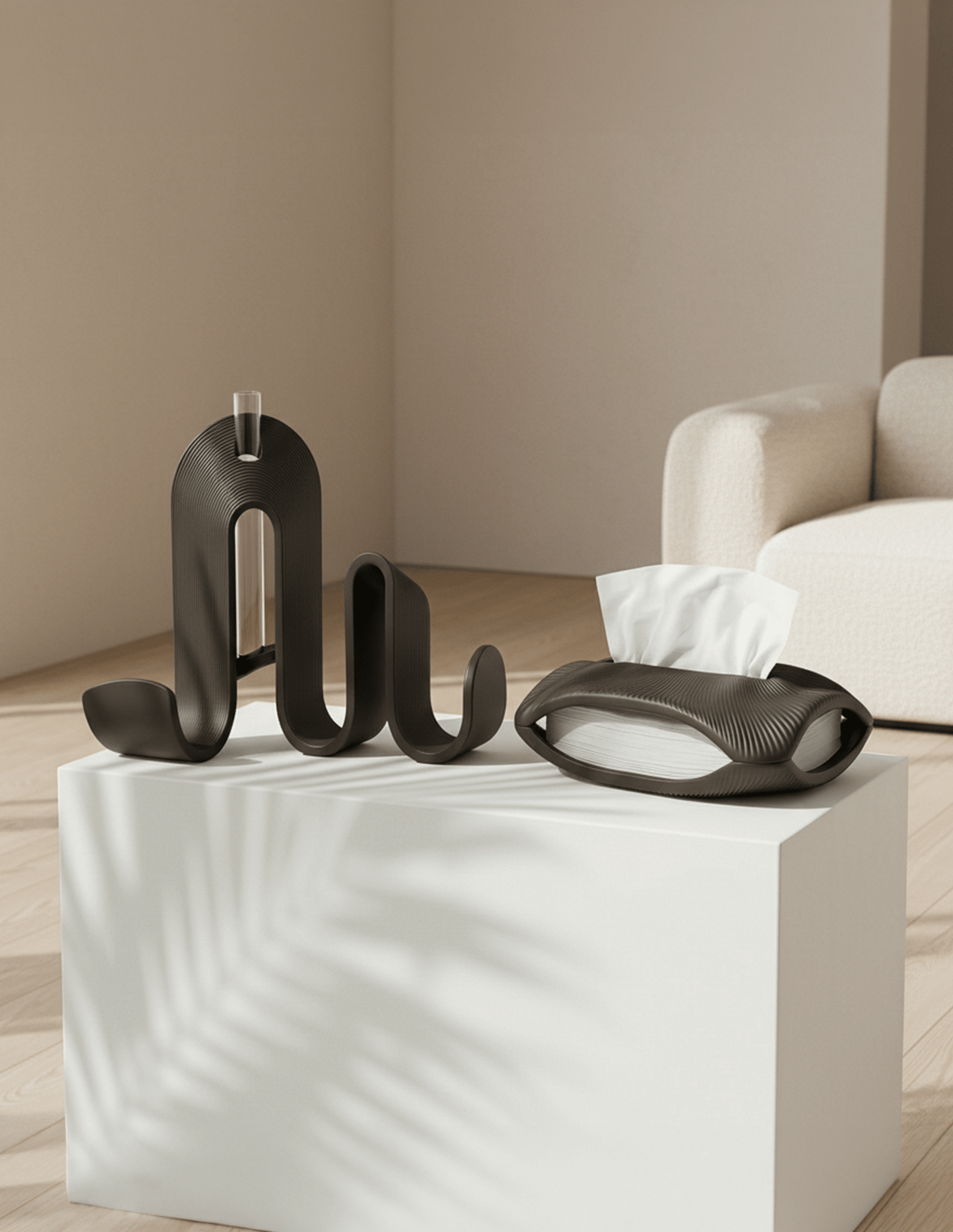 AMINI STRIA Entry Set in Charcoal — book holder and tissue holder on a white cube pedestal in a neutral living room
