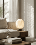AMINI STRIA Lamp in Charcoal — lit on a wooden side table beside a sofa in a warm interior