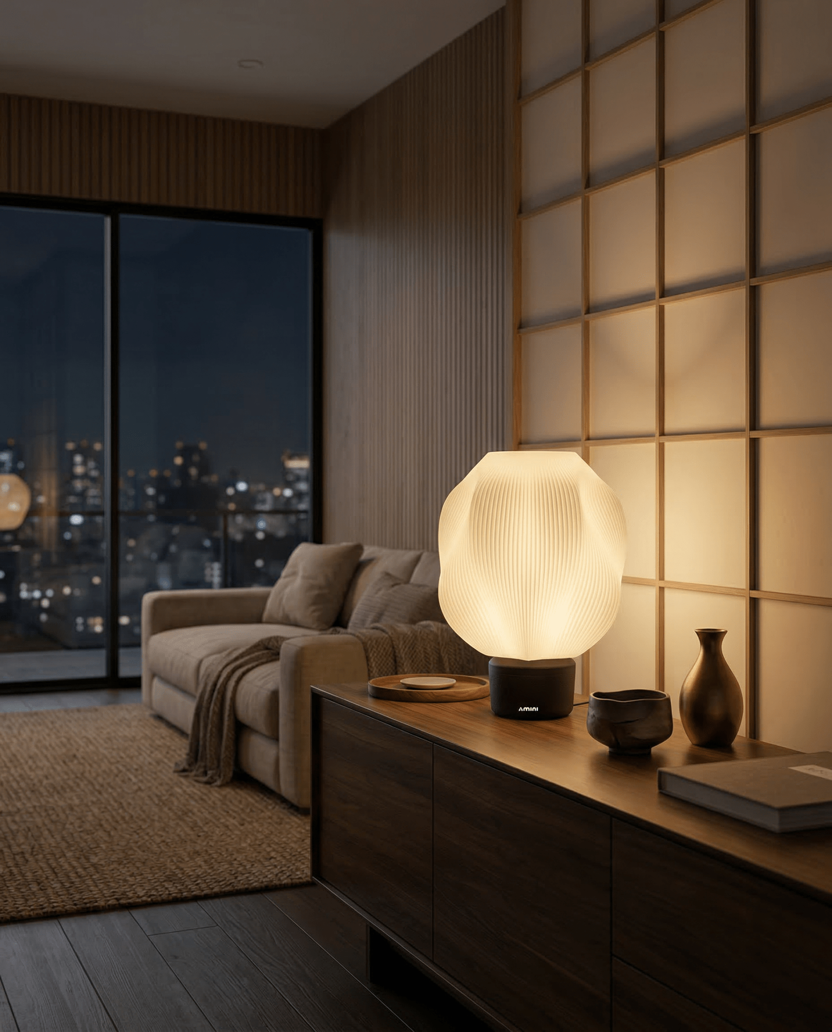 AMINI STRIA Lamp in Charcoal — lit at night on a sideboard in a Japanese-style room with warm glow and city skyline