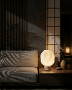 AMINI STRIA Lamp in Cream — lit at night on a low sideboard in a dark Japanese room with cherry blossom branch