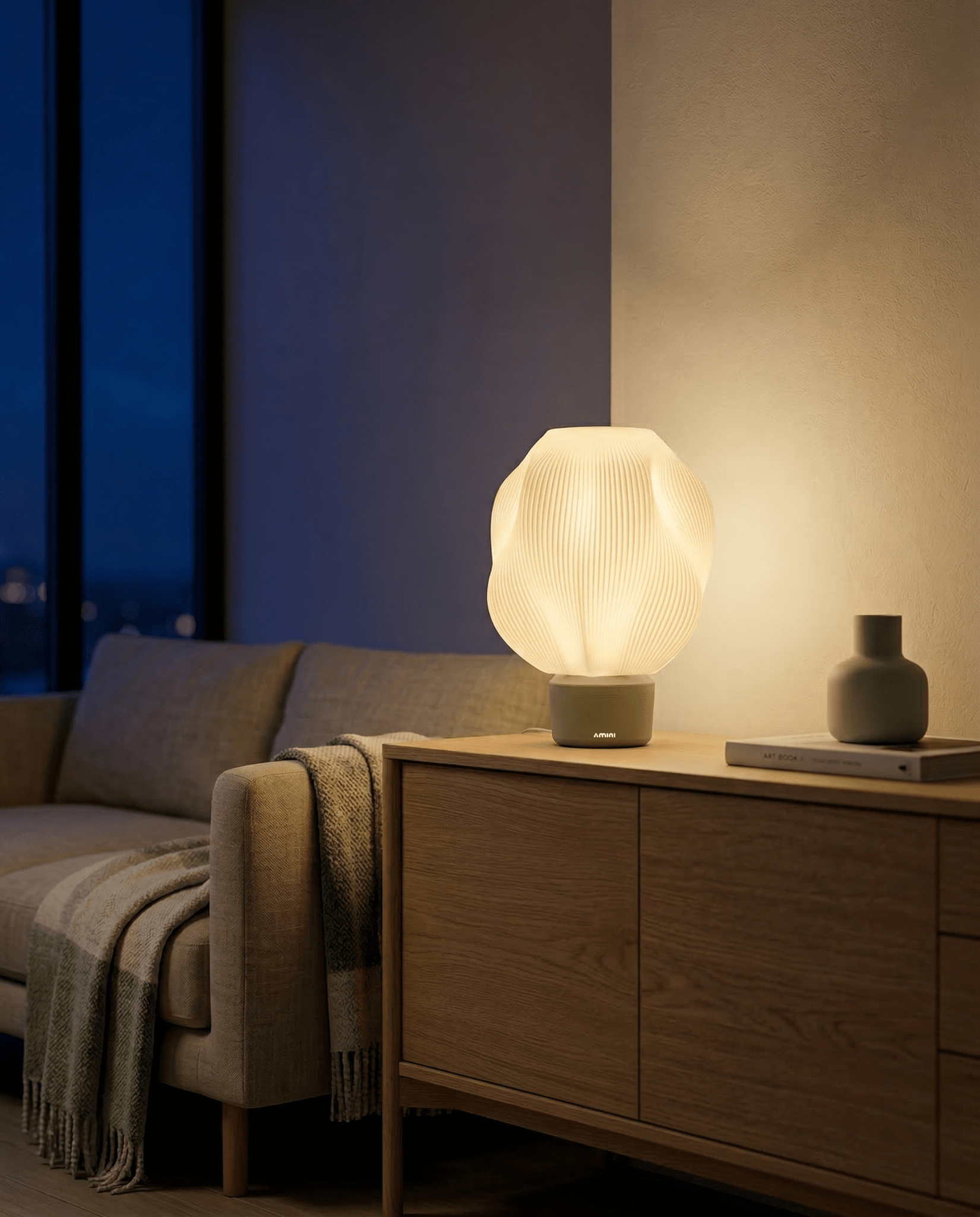 AMINI STRIA Lamp in Pistachio — lit at night on a sideboard in a modern room with blue-toned ambiance and city lights
