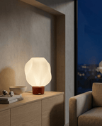 AMINI STRIA Lamp in Terracotta — lit at night on a sideboard with city view through window and cotton flower bowl