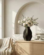 AMINI STRIA Vase in Charcoal — with white ranunculus and eucalyptus on a light wood sideboard